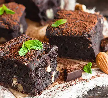 Teller mit Brownie, Mandeln und Topping aus Schokopulver mit Minze.