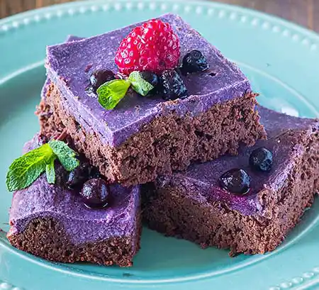 Teller mit Blaubeer-Ricotta-Brownie und Beeren-Minz-Topping.