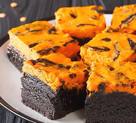 Teller mit Brownies mit Orangen-Cheescake-Topping.