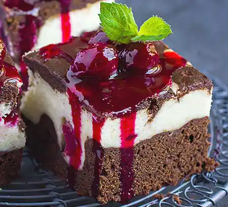 Teller mit Brownie-Cheescake mit Kirschen und Kirschsoße.