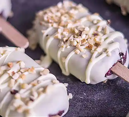 Cakesiscles in weißer Schoklade mit Nussstreuseln.