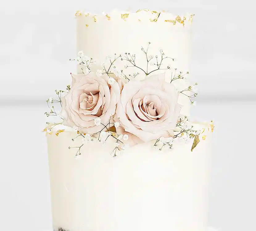 2-stöckige weiße Hochzeitstorte mit Blattgold und Blumendekor.