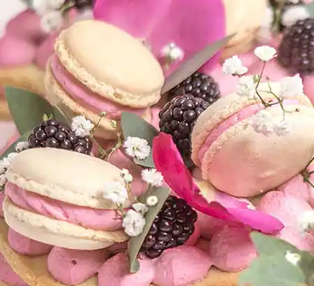 Tisch mit Macarons, rosafarbenen Füllung und Brombeeren.