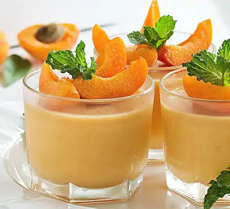 Gläser mit Pana Cotta aus gekochter Sahne mit Tonka-Bohne und frischer Aprikose.