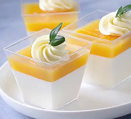 Quadratische Gläser mit Ricotta-Creme mit Sahne an Mango-Ganache aus weißer Schokolade und Mangopüree.