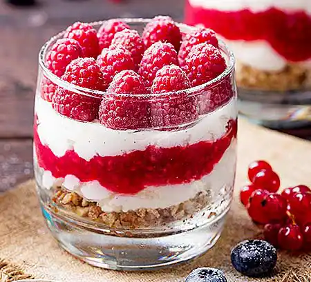 Gläser mit Himbeeren auf Ricottacreme und Mürbteigsplitter.
