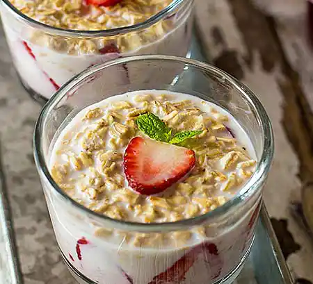 Gläser mit Joghurtcrème mit frischen Erdbeeren und Haferflocken.