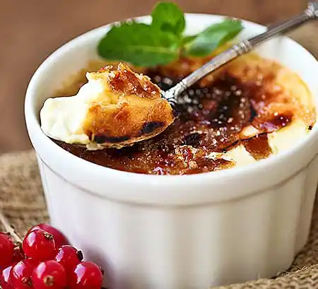 Porzelantopf mit Crème brûlée an Johannisbeeren und Minzgarnitur.