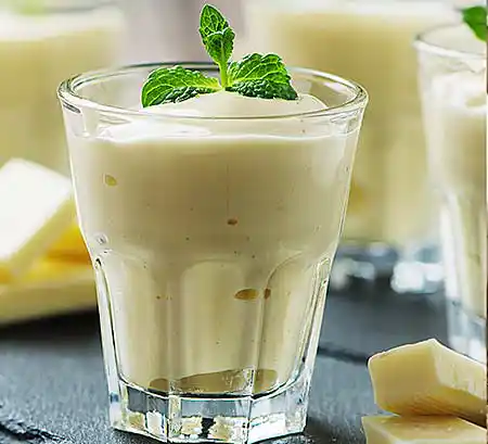 Gläser mit weißem Schokomousse mit pasteurisierten Eiern, frisch geschlagener Sahne und weißer Schokolade.