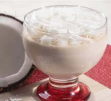 Glas mit Kokosnuss-Mousse aus Kokossahne und Mascarponecreme mit frisch gehobelten Kokosnüssen.