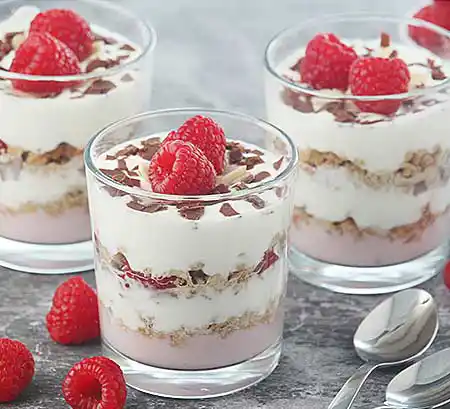 Gläser mit Himbeer-Joghut- und Mascarponecreme, frischen Himbeeren und Schokosplittern.