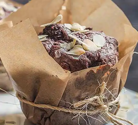 Schoko-Muffin mit Mandelgarnitur in Papier gewickelt.