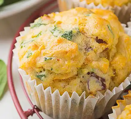 Muffin mit Spinat, Süßkartoffeln und Käse auf Teller.