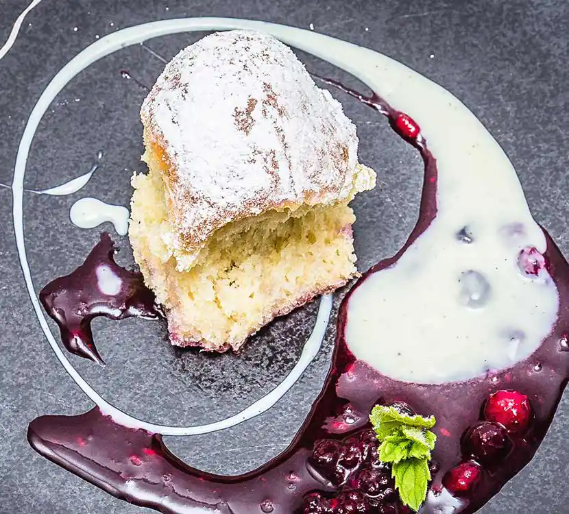 Teller mit Buchteln an Vanillesoße und Fruchtspiegel.