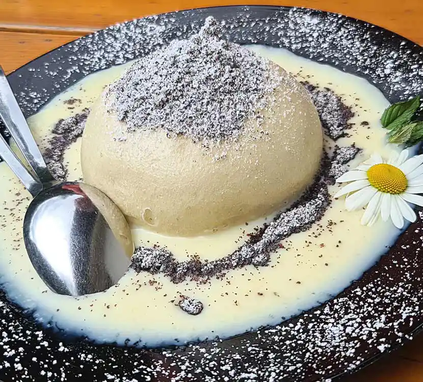Teller mit Germknödel in Vanillesauce.