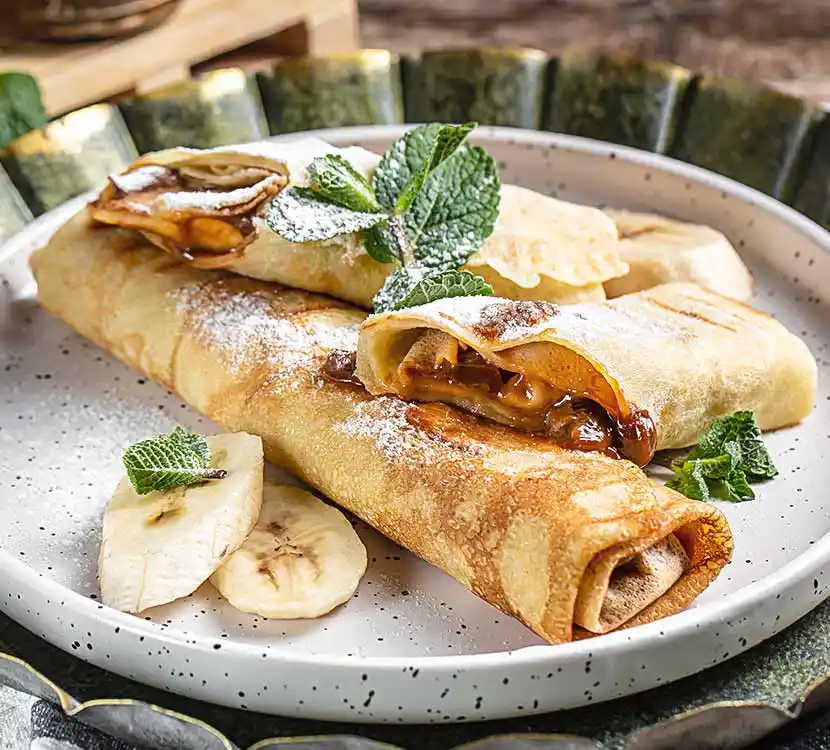 Teller mit zwei gerollten Pallatschinken.