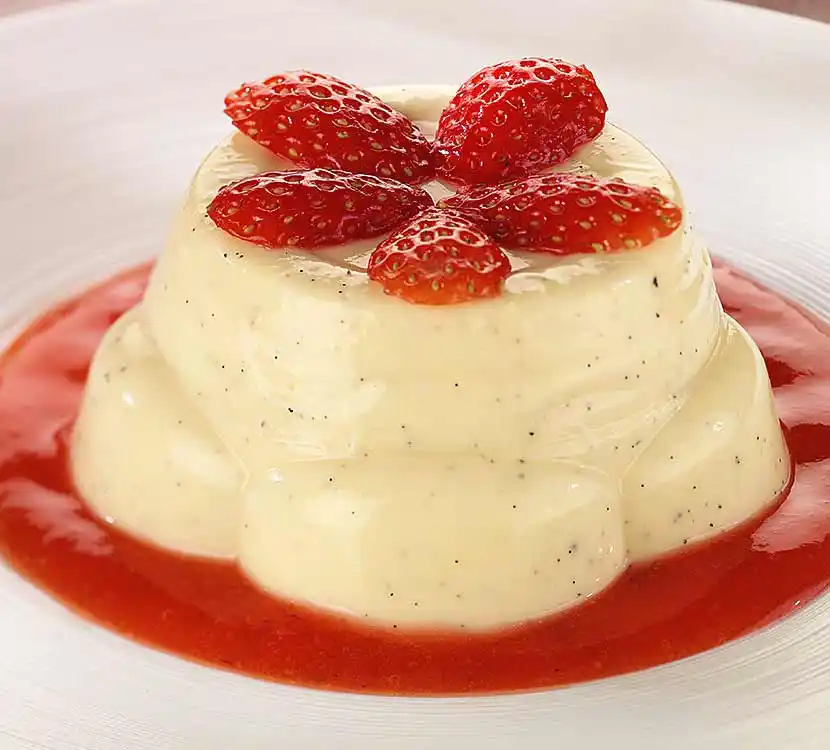 Teller mit hellem Pudding auf Erdbeer-Fruchtspiegel.