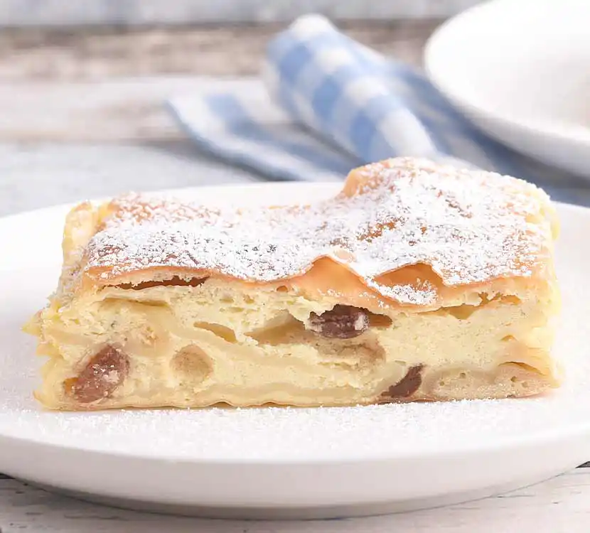 Stück Topfenstrudel mit Rosinen auf Teller.