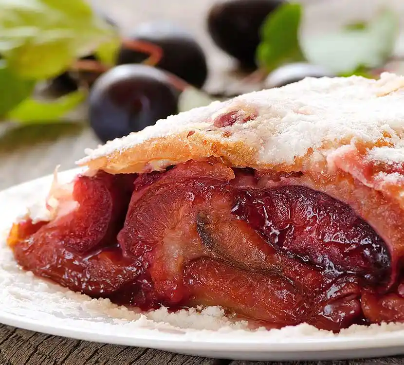 Angeschnittener Zwetschgenstrudel auf Teller.