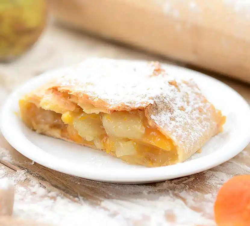 Angeschnittener Pfirsichstrudel auf Teller.