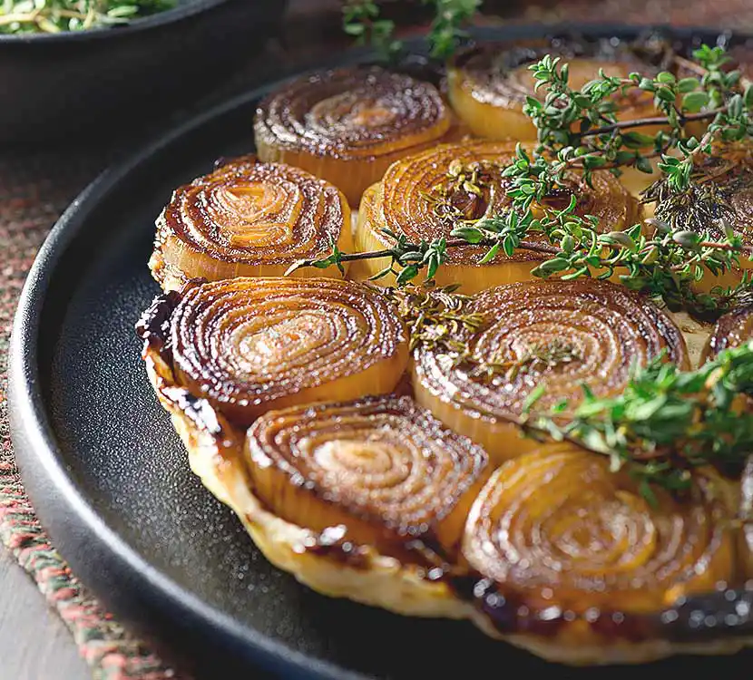 Teller mit Zwiebelkuchen und Kräutern.