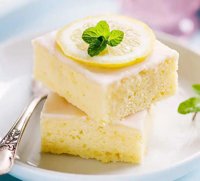 Teller mit 2 Stück Zitronenkuchen und Zitronenscheibe.