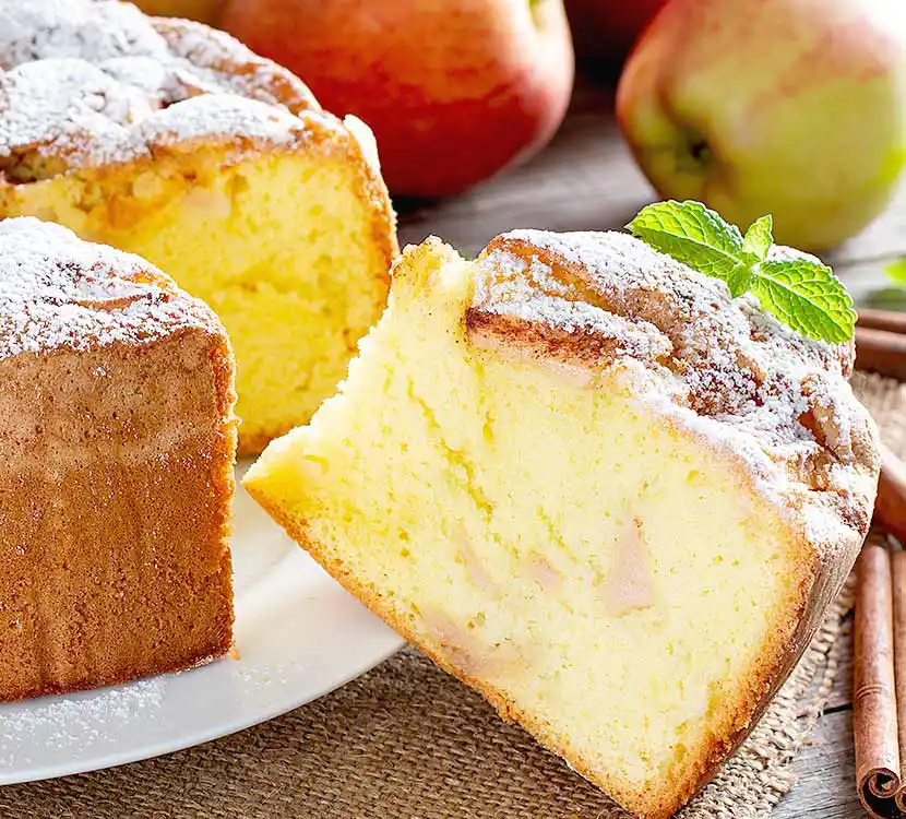 Teller mit angeschnittenem Vanillekuchen und Apfelstückchen.