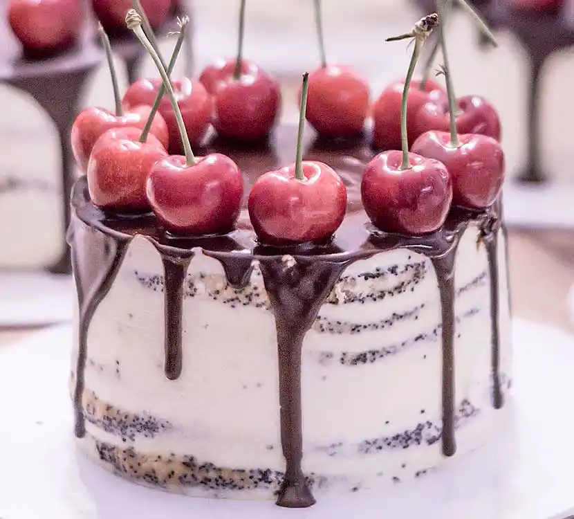 Weiße Semi Naked Torte mit Schoko-Drip und Kirschen.