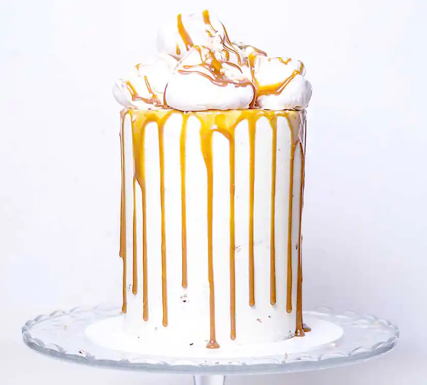 Teller mit weißer Torte und Karamell-Drip und Baiser.