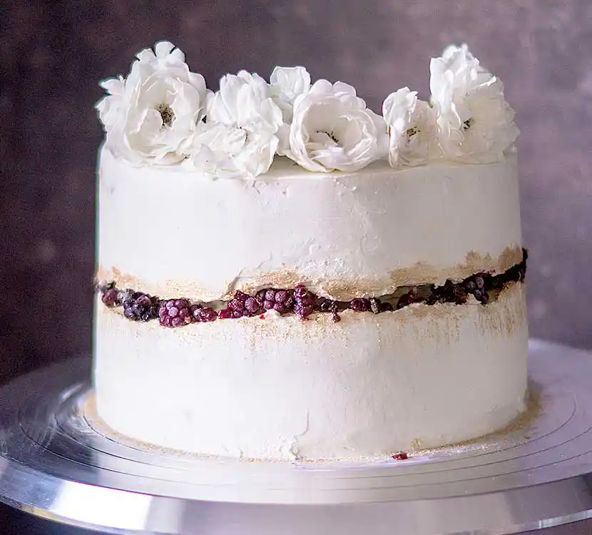 Teller mit weißer Torte im Fault Line Stil mit Blumendeko.