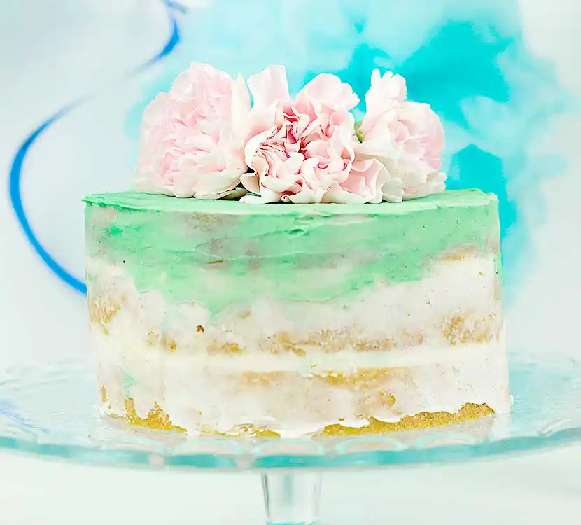 Teller mit weiß-grüner Torte im Ombréstil mit Blumendeko.