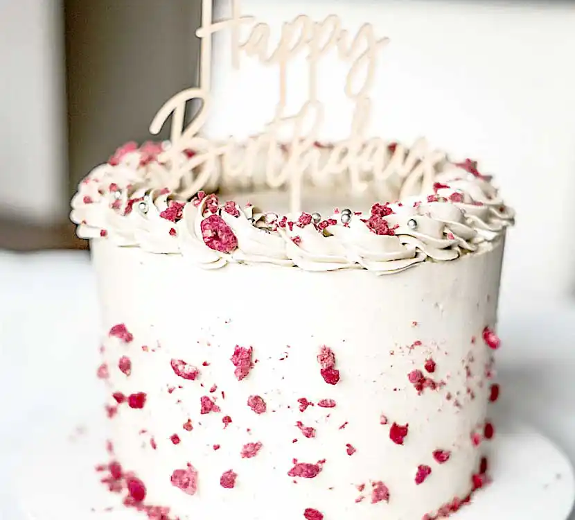 Weiße Geburtstagstorte mit Buttercreme und Trockenfrüchten.