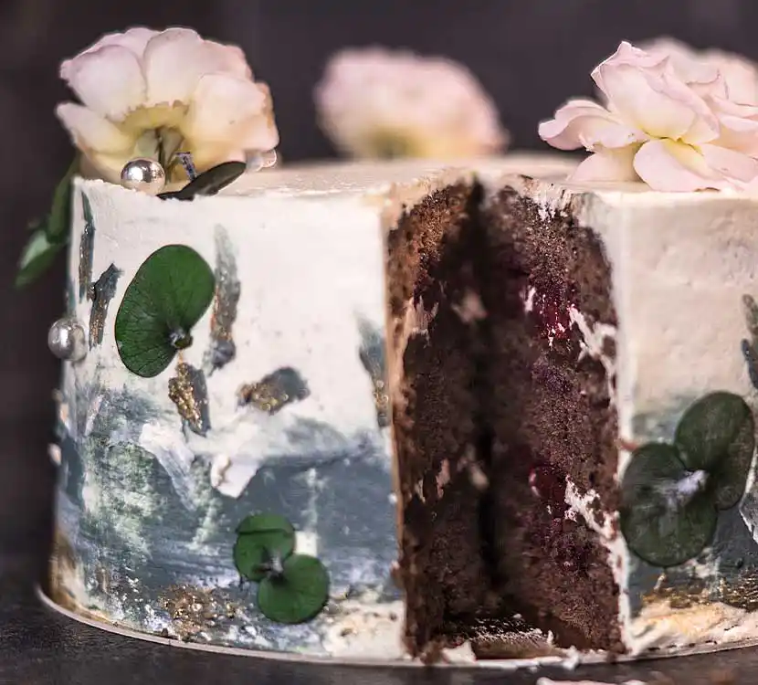 Kunstvoll bemalte, angeschnittene Torte mit Blumendeko.