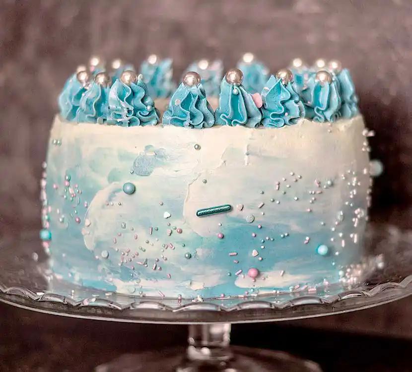 Teller mit blau eingestrichener Torte und blauer Buttercreme-Verziehrung.