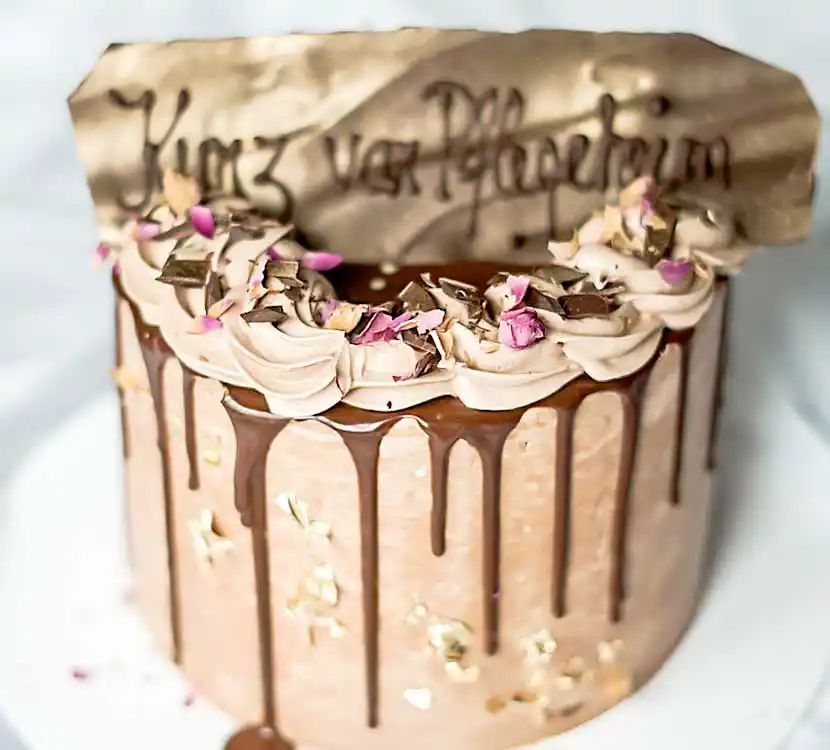 Goldene Torte mit Schoko-Drip und Namenskarte.
