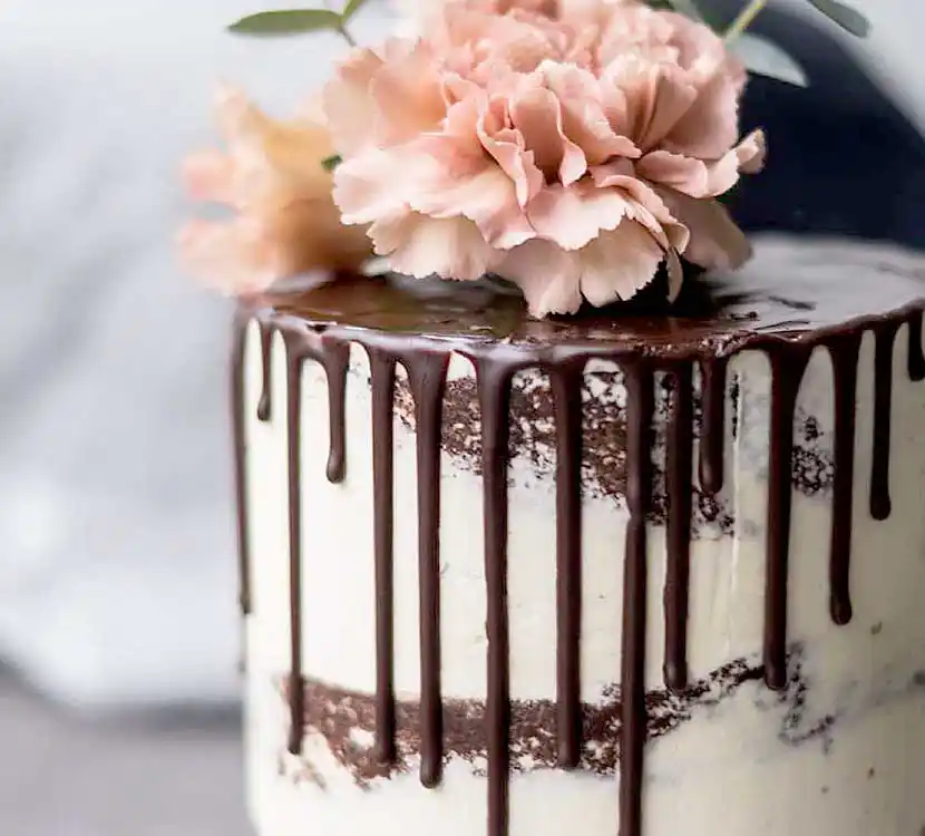 Weiße Torte mit Drip aus Schokolade und Blumendekor.