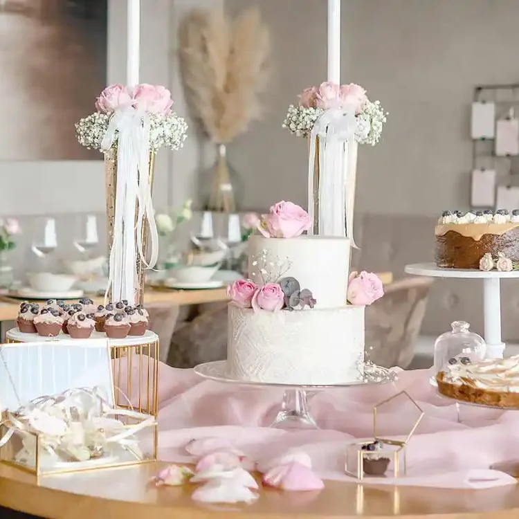 Gedeckte Tische mit Hochzeitstorte, Torte, Tartes Cupcakes und Dekoration Rosen.