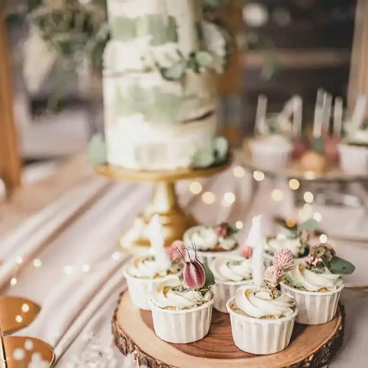 Gedeckter Tisch mit Hochzeitstorte, Cupcakes und Cakepops auf Teller im Bohostil.